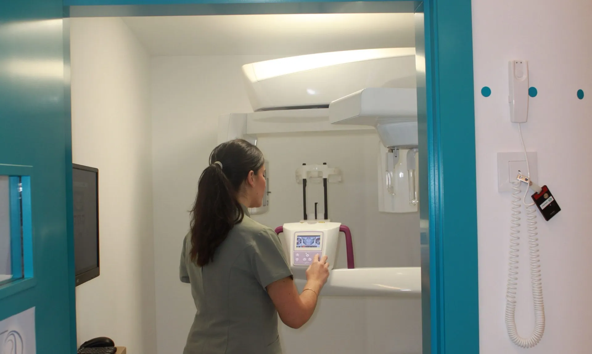 Sala de radiología 3D de la clínica con el equipo panorámico y una profesional manejándolo